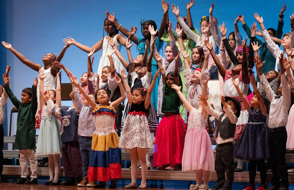 Sandy Lake Academy junior choir singing with arms raised at the Spring Celebration